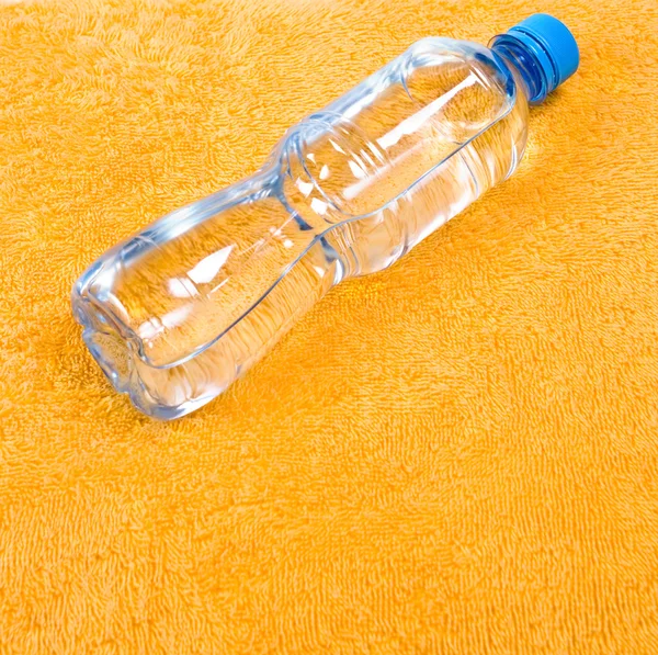 Água em garrafa em toalha de laranja — Fotografia de Stock
