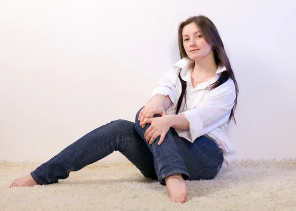 Een vrouw zit op het tapijt. — Stockfoto