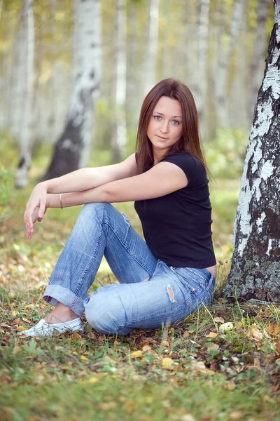 Una joven con el pelo largo en el bosque de otoño . — Foto de Stock