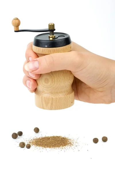 Wooden spice handmill in hand and allspice — Stock Photo, Image