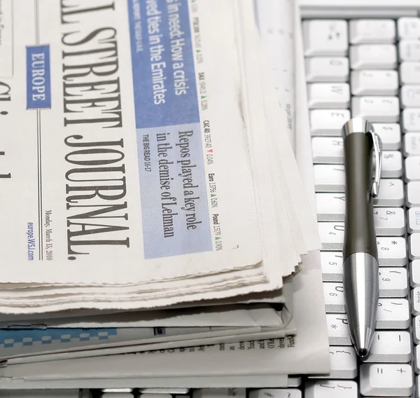 Newspapers and pen on notebook keyboard — Stock Photo, Image