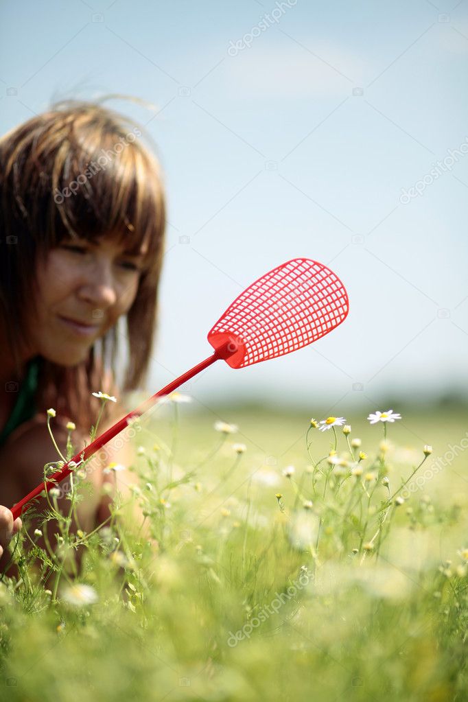 Woman with fly swatter in hand hunting for insect
