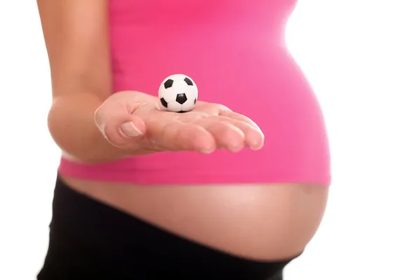 Ventre de femme enceinte avec ballon de football à la main — Photo