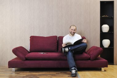 Young man relaxing in modern living room clipart