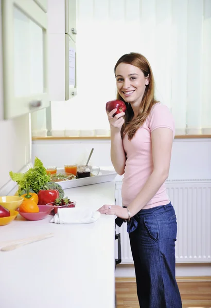 Ευτυχής νεαρή γυναίκα με το μήλο στην κουζίνα — Φωτογραφία Αρχείου