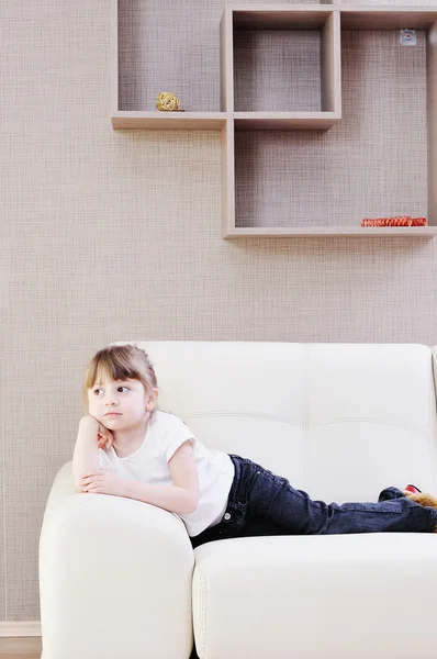 Menina bonito no sofá na enxada — Fotografia de Stock