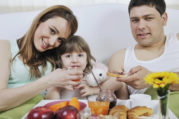 Šťastná mladá rodina jíst snídani v posteli — Stock fotografie
