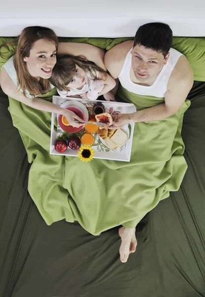 快乐的年轻家庭在床上吃早餐 — 图库照片