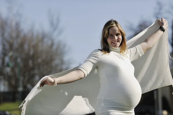 Счастливая молодая беременная женщина на открытом воздухе — стоковое фото