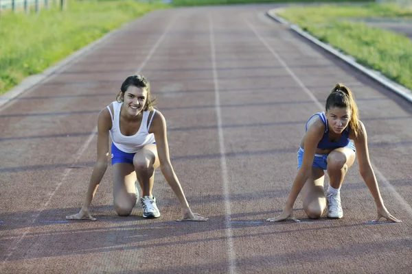Dos chicas corriendo en pista de atletismo — Foto de Stock