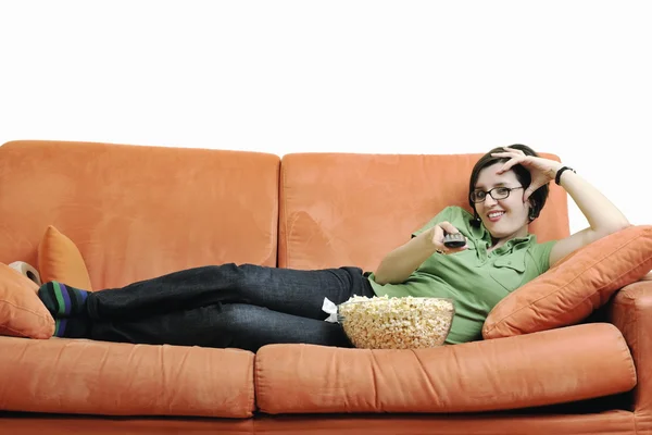 Młoda kobieta jeść popcorn na kanapie pomarańczowy — Zdjęcie stockowe