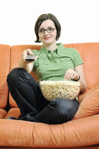 Ung kvinna äta popcorn på orange soffa — Stockfoto