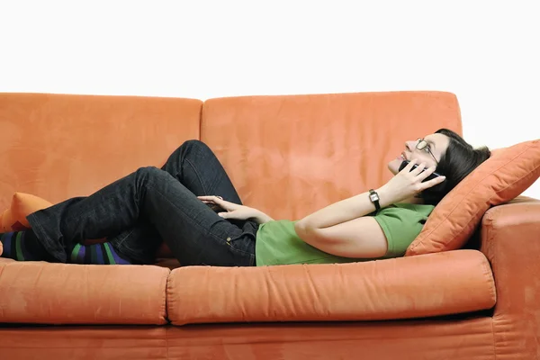 若い女性はオレンジ色のソファでリラックスします。 — ストック写真