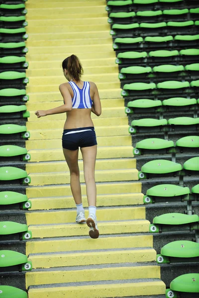 Mulher correndo no estádio de atletismo — Fotografia de Stock