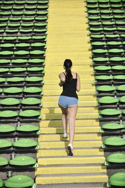 Mulher correndo no estádio de atletismo — Fotografia de Stock