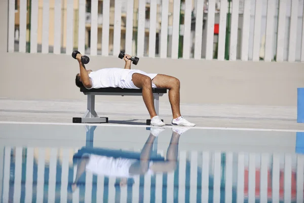 Junger gesunder Sportler turnt am Pool — Stockfoto