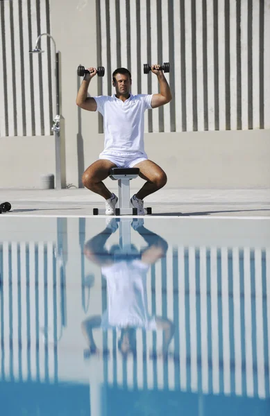 Молодой здоровый спортсмен упражнения у бассейна — стоковое фото