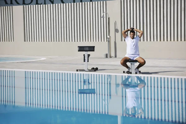 Молодой здоровый спортсмен упражнения у бассейна — стоковое фото