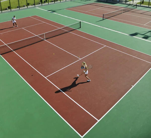 Lyckliga unga paret spela tennisspel utomhus — Stockfoto