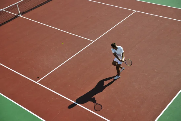 Молодой человек играет в теннис на открытом воздухе — стоковое фото