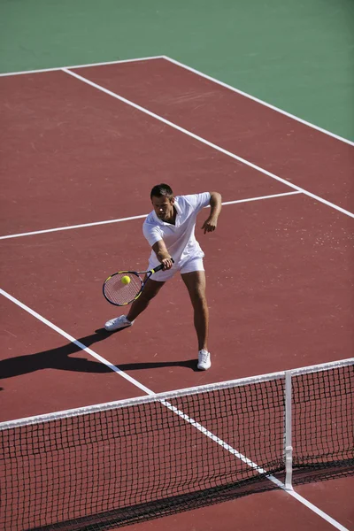 Молодой человек играет в теннис на открытом воздухе — стоковое фото
