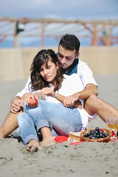 Jovem casal desfrutando de piquenique na praia — Fotografia de Stock