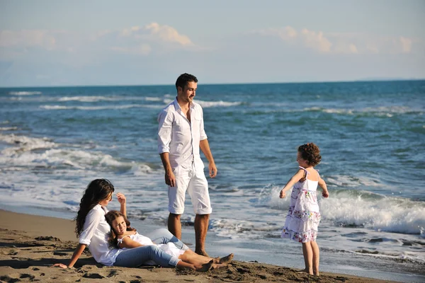 Happy family playing with dog on beach — Stock Photo, Image