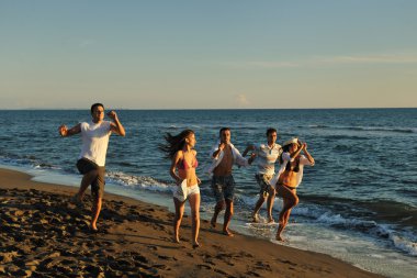 Happy family playing with dog on beach clipart