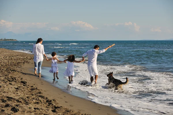 Glückliche Familie spielt mit Hund am Strand — Stockfoto