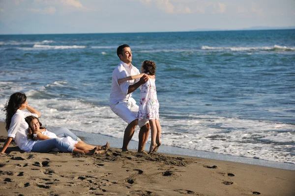 Szczęśliwa rodzina bawi się z psem na plaży — Zdjęcie stockowe