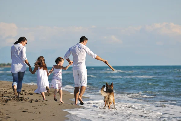 Šťastná rodina hrát se psem na pláži — Stock fotografie