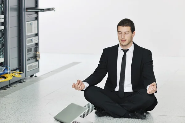 英俊的年轻商业黑衣适合练瑜伽和代表应力控制概念的同时在网络服务器机房放松 — 图库照片