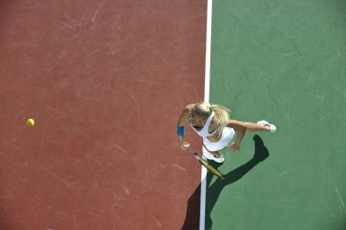 genç kadın oyun Tenis açık portakal Tenis alanında erken sabah saat yerleştirmek.