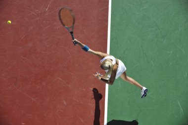 genç kadın oyun Tenis açık portakal Tenis alanında erken sabah saat yerleştirmek.