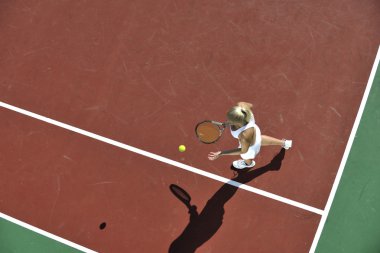 genç kadın oyun Tenis açık portakal Tenis alanında erken sabah saat yerleştirmek.