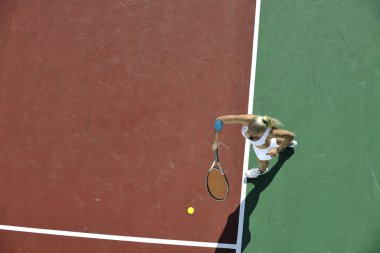 genç kadın oyun Tenis açık portakal Tenis alanında erken sabah saat yerleştirmek.