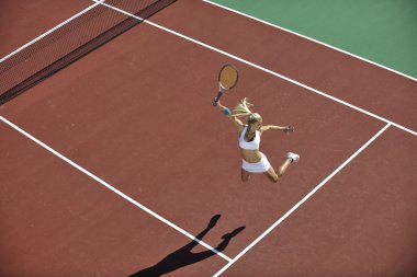 genç kadın oyun Tenis açık portakal Tenis alanında erken sabah saat yerleştirmek.