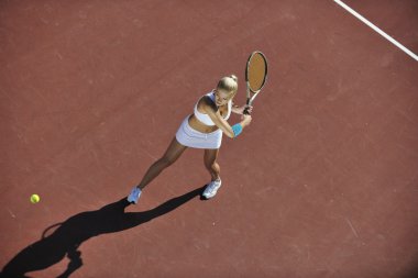 genç kadın oyun Tenis açık portakal Tenis alanında erken sabah saat yerleştirmek.