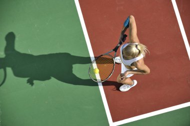 genç kadın oyun Tenis açık portakal Tenis alanında erken sabah saat yerleştirmek.