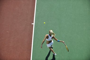 genç kadın oyun Tenis açık portakal Tenis alanında erken sabah saat yerleştirmek.