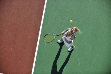 genç kadın oyun Tenis açık portakal Tenis alanında erken sabah saat yerleştirmek.