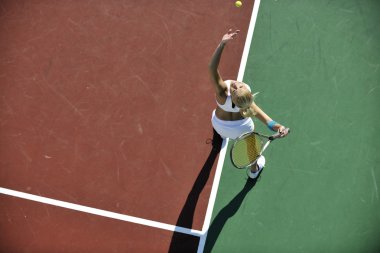 genç kadın oyun Tenis açık portakal Tenis alanında erken sabah saat yerleştirmek.