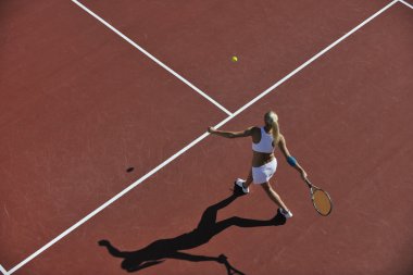 genç kadın oyun Tenis açık portakal Tenis alanında erken sabah saat yerleştirmek.