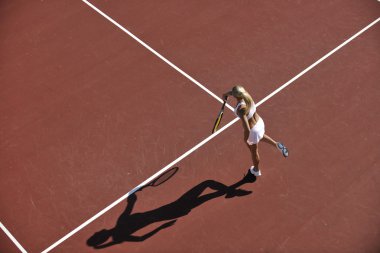 genç kadın oyun Tenis açık portakal Tenis alanında erken sabah saat yerleştirmek.