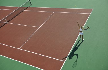 genç kadın oyun Tenis açık portakal Tenis alanında erken sabah saat yerleştirmek.