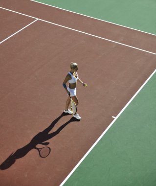 genç kadın oyun Tenis açık portakal Tenis alanında erken sabah saat yerleştirmek.