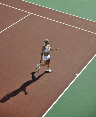 genç kadın oyun Tenis açık portakal Tenis alanında erken sabah saat yerleştirmek.