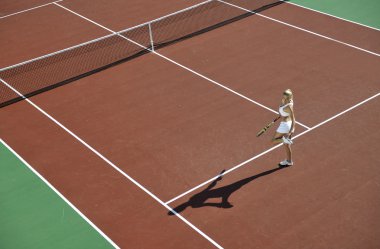 genç kadın oyun Tenis açık portakal Tenis alanında erken sabah saat yerleştirmek.