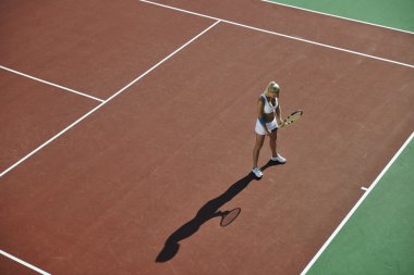 genç kadın oyun Tenis açık portakal Tenis alanında erken sabah saat yerleştirmek.