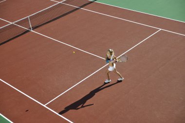 genç kadın oyun Tenis açık portakal Tenis alanında erken sabah saat yerleştirmek.